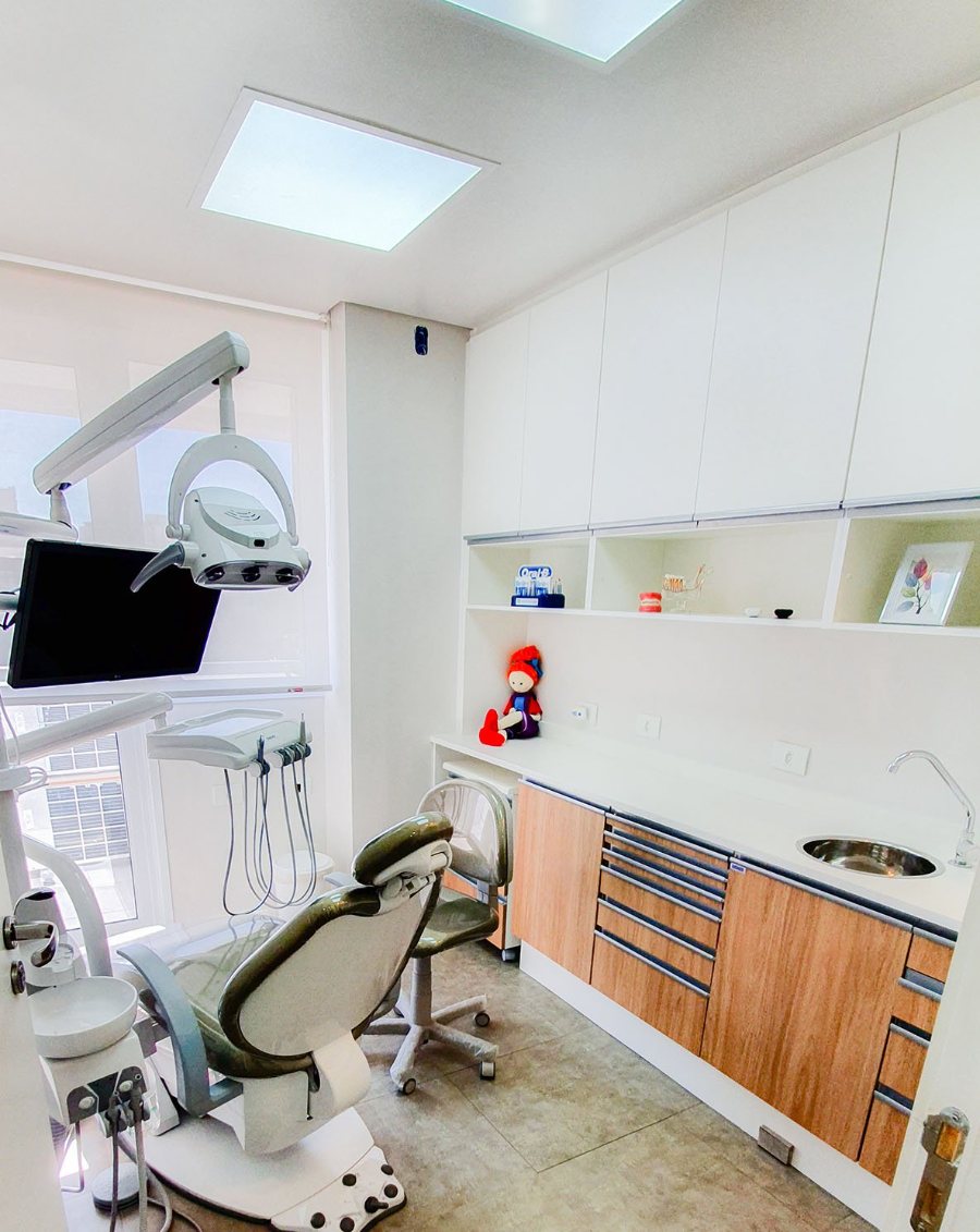 Cadeira odontológica e armários de madeira na sala de atendimento