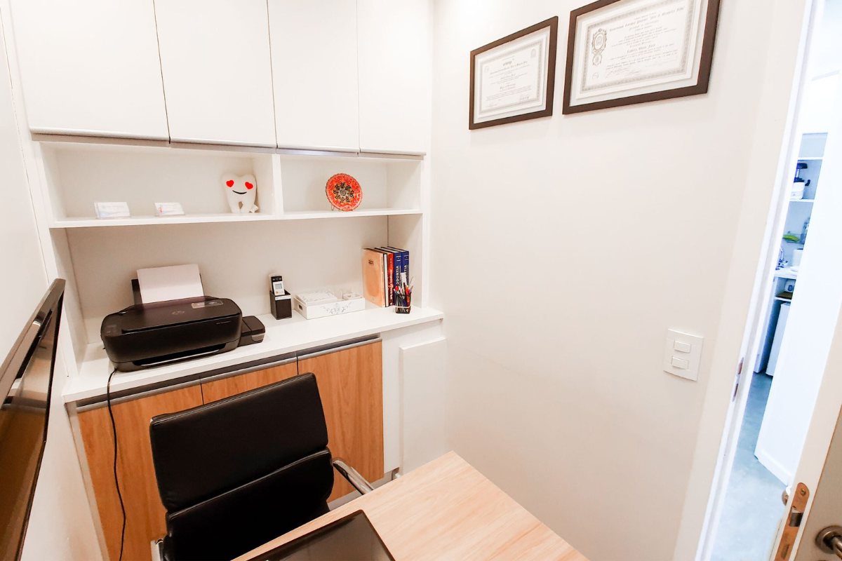 Consultório da Farac Odontologia, com mesa de atendimento e diplomas na parede