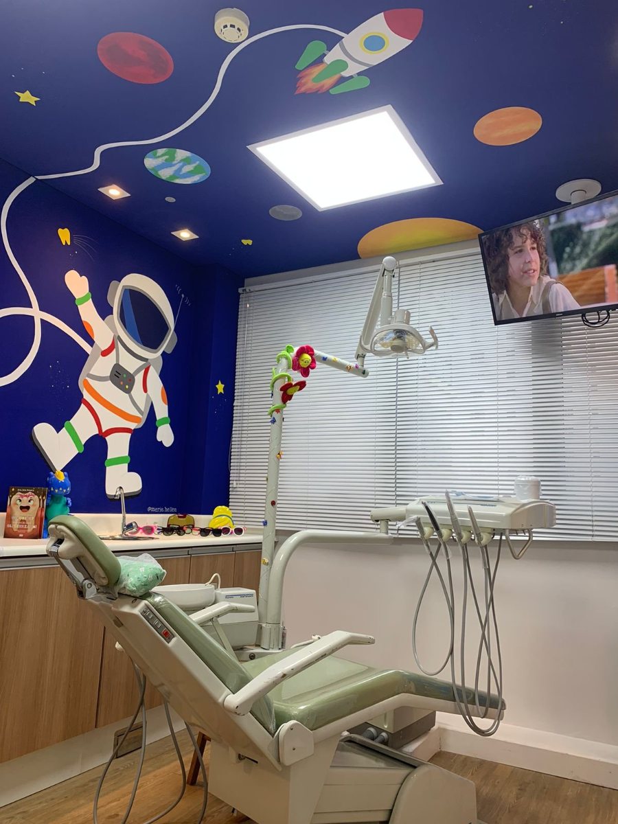 Sala de atendimento infantil da Farac Júnior, com parede azul pintada com astronauta e foguete